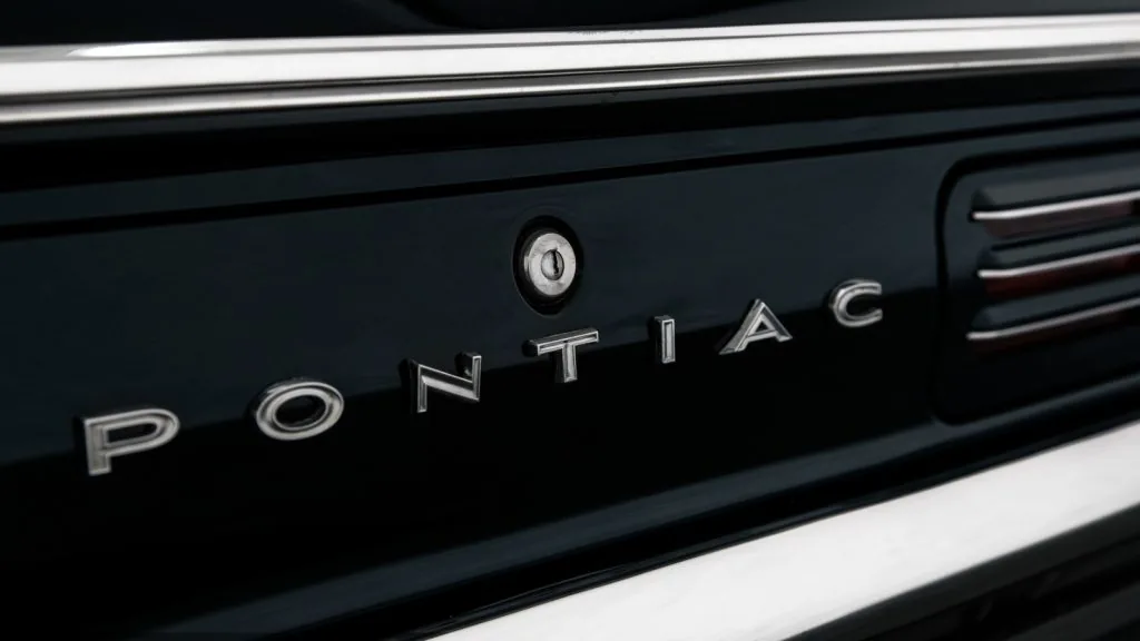 Nahaufnahme eines Kofferraums mit dem Wort „Pontiac“ in Chrombuchstaben und einem Schlüsselloch darüber.