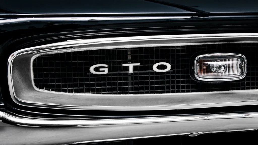 Nahaufnahme eines schwarzen Kühlergrills eines Oldtimers mit den deutlich sichtbaren Buchstaben „GTO“ in der Mitte.